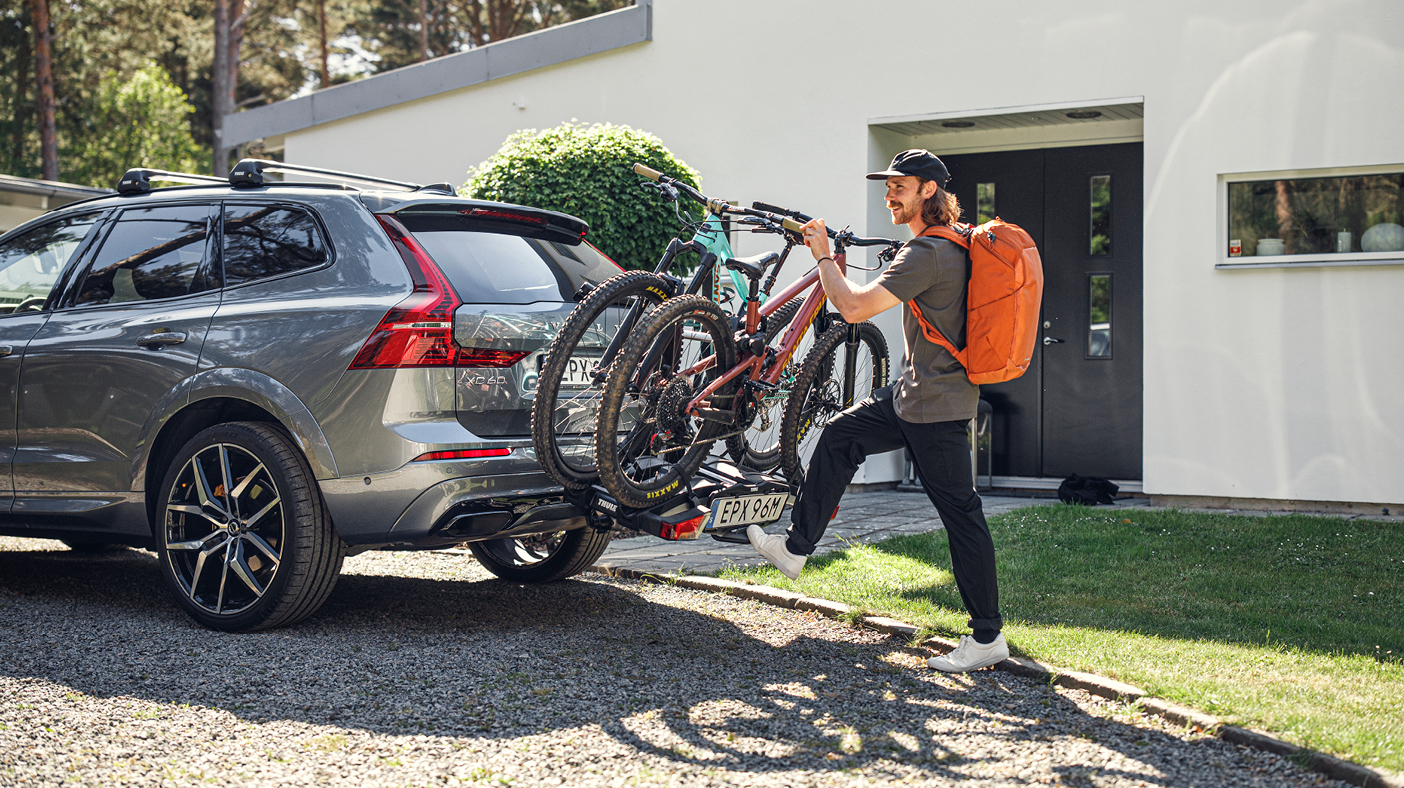 Homme qui accroche ses vélos au support à vélo attaché à son auto